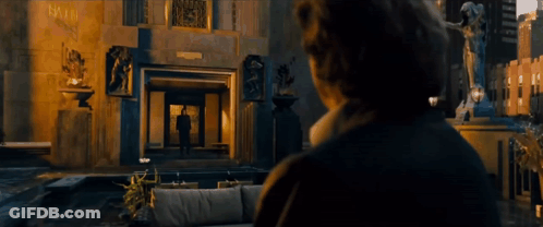 A Man Stands In Front Of A Fountain In Front Of A Large Building GIF