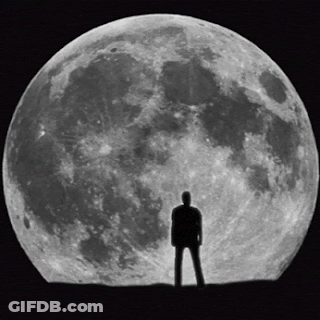 A Man Stands In Front Of A Full Moon In A Black And White Photo GIF