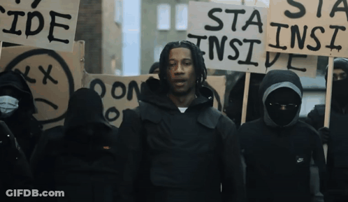 A Man Stands In Front Of A Group Of People Holding Signs Including One That Says " Sta Ins Ide " GIF