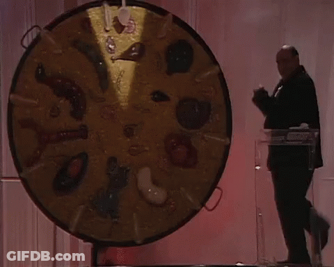 A Man Stands In Front Of A Large Circular Display Of Food Items GIF