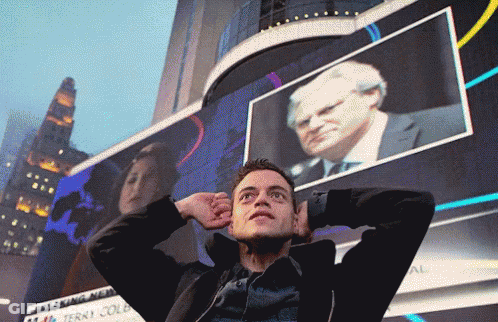 A Man Stands In Front Of A Large Screen That Says Breaking News GIF