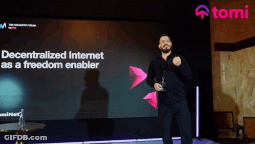 A Man Stands In Front Of A Large Screen That Says " Decentralized Internet As A Freedom Enabler " GIF