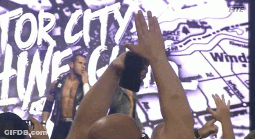 A Man Stands In Front Of A Large Screen That Says Tor City Hwc GIF