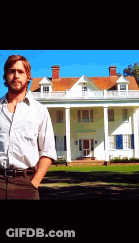 A Man Stands In Front Of A Large White House With His Hands In His Pockets GIF