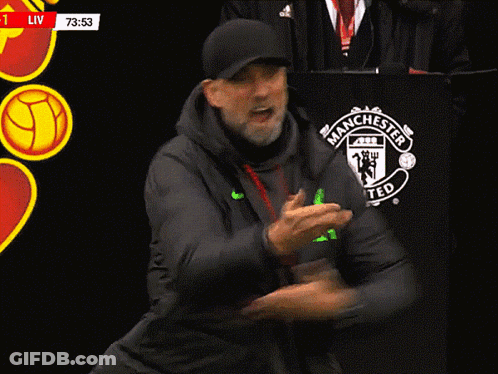 A Man Stands In Front Of A Manchester United Logo GIF
