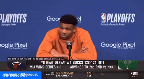 A Man Stands In Front Of A Microphone In Front Of A Screen That Says Playoffs On It GIF