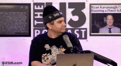 A Man Stands In Front Of A Microphone In Front Of A Sign That Says 13 Podcast GIF