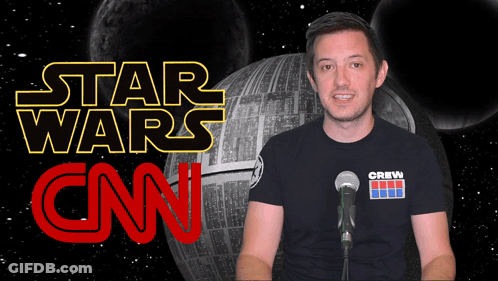 A Man Stands In Front Of A Microphone In Front Of A Star Wars Logo GIF