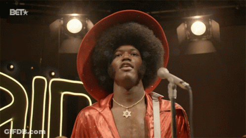 A Man Stands In Front Of A Microphone With A Bet Logo In The Background GIF