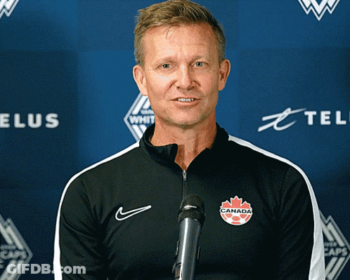 A Man Stands In Front Of A Microphone With A Canada Logo On His Chest GIF