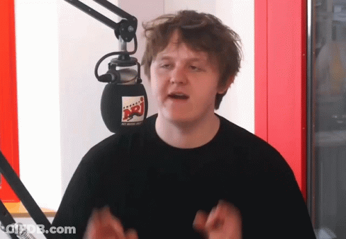 A Man Stands In Front Of A Microphone With A Sticker On It That Says Nrj GIF