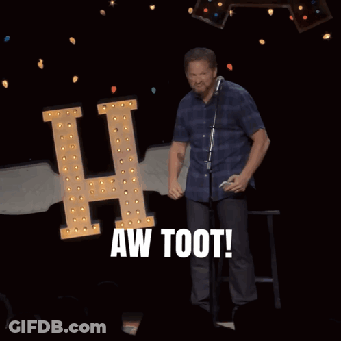 A Man Stands In Front Of A Microphone With The Words Aw Toot Behind Him GIF