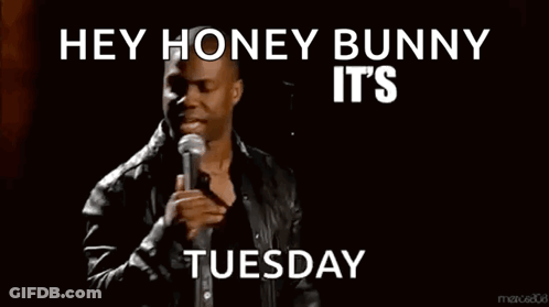 A Man Stands In Front Of A Microphone With The Words Hey Honey Bunny It 'S About To Go Down Tuesday Below Him GIF