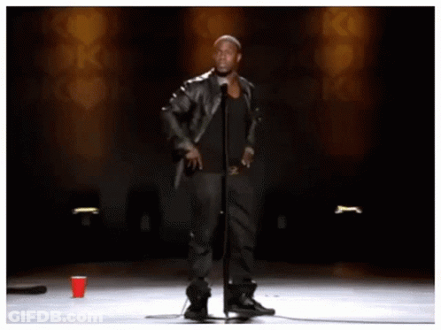 A Man Stands In Front Of A Microphone With The Words " Look Look Look " Behind Him GIF