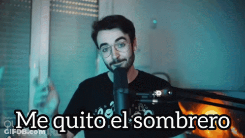 A Man Stands In Front Of A Microphone With The Words Me Quito El Sombrero Below Him GIF