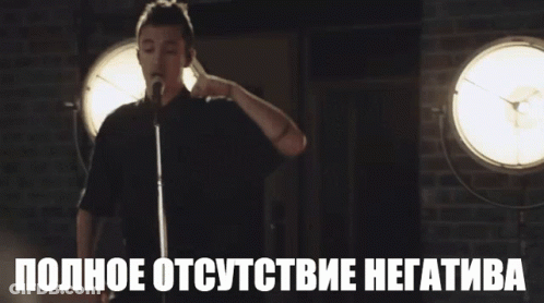 A Man Stands In Front Of A Microphone With The Words " Полное Отсутствие Негатива " Below Him GIF
