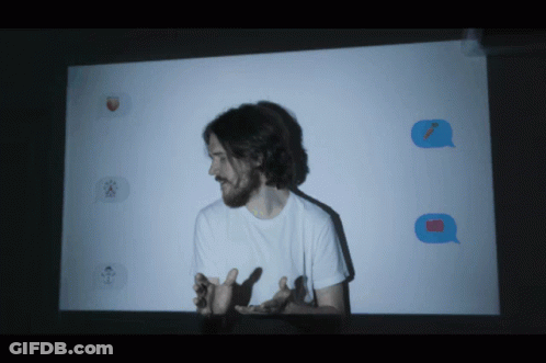 A Man Stands In Front Of A Projector Screen With Emojis Projected GIF