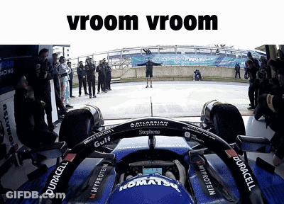 A Man Stands In Front Of A Race Car With The Words Vroom Vroom Written Above Him GIF