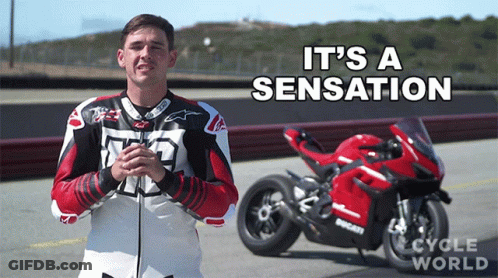 A Man Stands In Front Of A Red Ducati Motorcycle With The Words It 'S A Sensation Written Above Him GIF