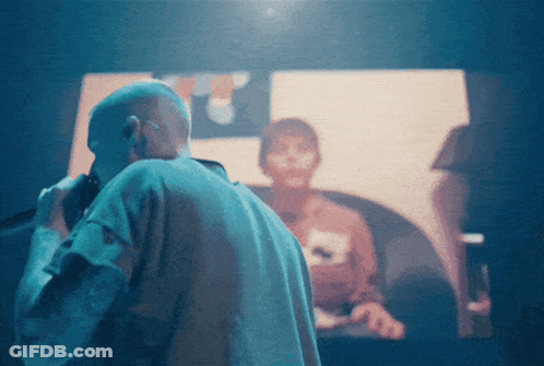 A Man Stands In Front Of A Screen That Says ' A ' On It GIF