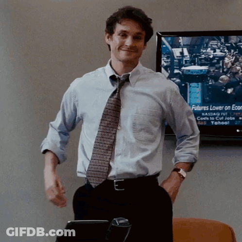 A Man Stands In Front Of A Screen That Says Futures Lower On Economic News GIF