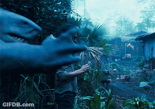 A Man Stands In Front Of A Shark That Is Eating A Palm Tree GIF