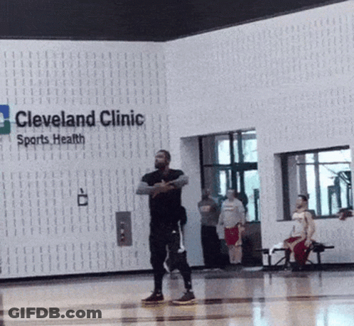 A Man Stands In Front Of A Sign For Cleveland Clinic Sports Health GIF