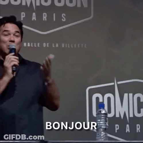 A Man Stands In Front Of A Sign That Says Comic Con Paris GIF
