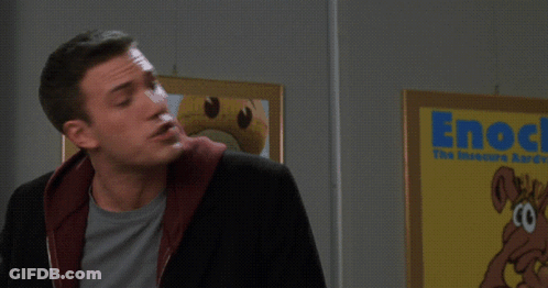 A Man Stands In Front Of A Sign That Says Enock Survey Says GIF