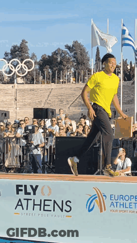 A Man Stands In Front Of A Sign That Says Fly Athens On It GIF