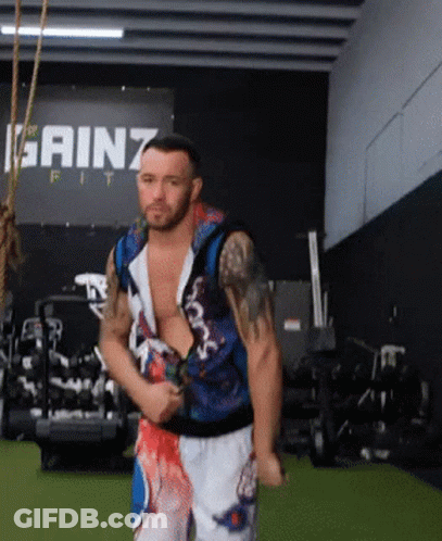 A Man Stands In Front Of A Sign That Says Gainz GIF