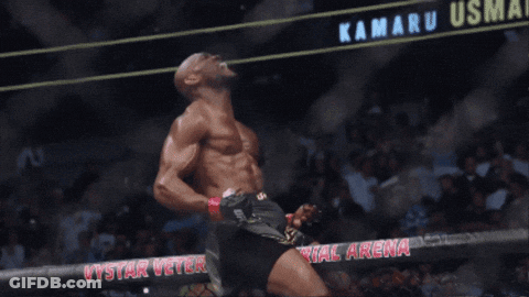 A Man Stands In Front Of A Sign That Says Kamaru Usma On It GIF