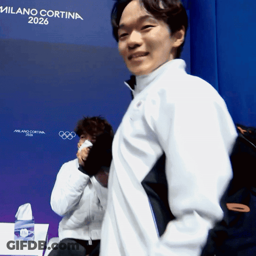 A Man Stands In Front Of A Sign That Says Milano Cortina GIF