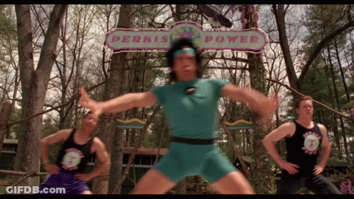 A Man Stands In Front Of A Sign That Says Perkis Power GIF