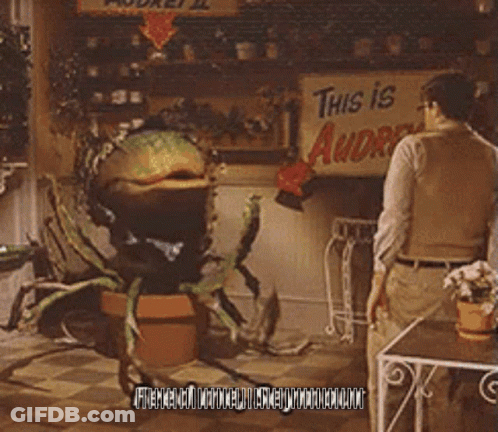 A Man Stands In Front Of A Sign That Says " This Is Audrey " GIF