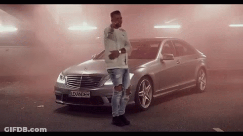 A Man Stands In Front Of A Silver Mercedes With The License Plate Lexander GIF