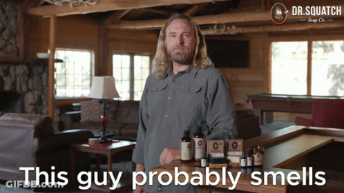A Man Stands In Front Of A Table With Dr. Squatch Soap On It GIF
