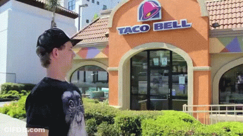 A Man Stands In Front Of A Taco Bell GIF