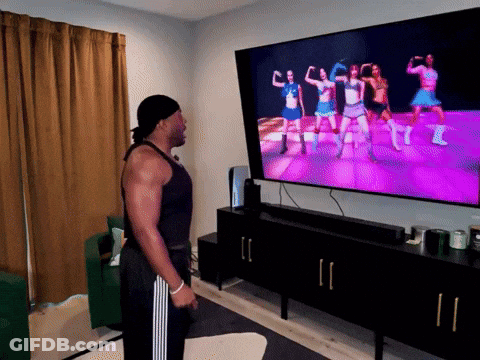 A Man Stands In Front Of A Television Watching A Video GIF