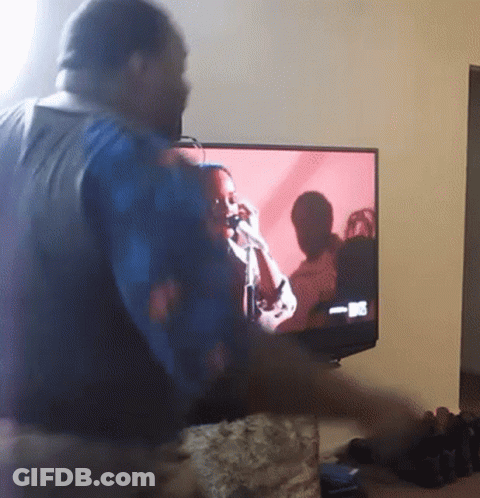 A Man Stands In Front Of A Tv Screen That Says ' Nbc ' On It GIF