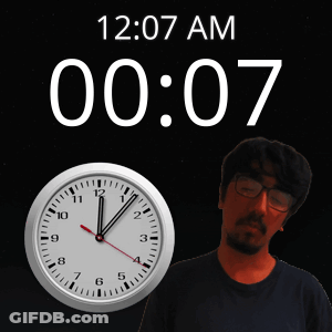 A Man Stands In Front Of A Wall Clock That Says 12:07 Am GIF