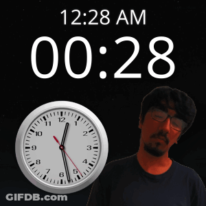 A Man Stands In Front Of A Wall Clock That Says 12:28 Am GIF