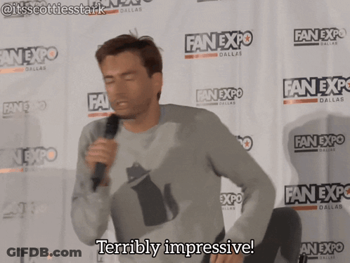 A Man Stands In Front Of A Wall That Says Fan Expo Dallas GIF