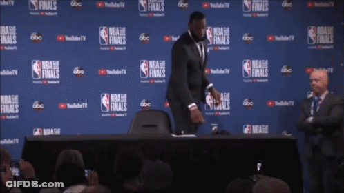A Man Stands In Front Of A Wall That Says Nba Finals On It GIF