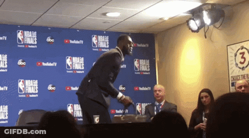 A Man Stands In Front Of A Wall That Says Nba Finals On It GIF