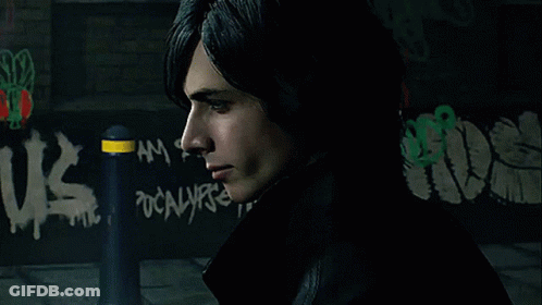 A Man Stands In Front Of A Wall With Graffiti That Says Us GIF