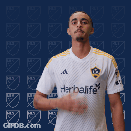 A Man Stands In Front Of A Wall With Mls Logos GIF