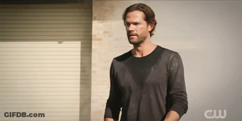 A Man Stands In Front Of A Wall With The Letters Cw On The Bottom GIF
