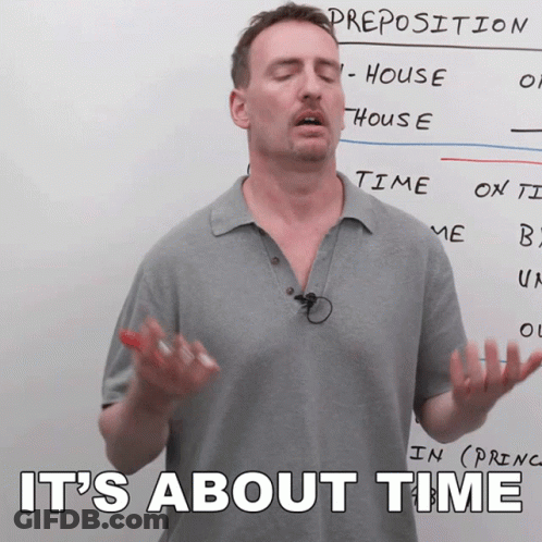 A Man Stands In Front Of A White Board With The Words " It 'S About Time " Written On It GIF