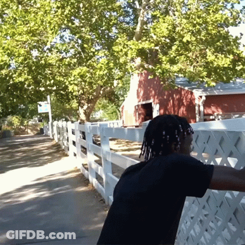 A Man Stands In Front Of A White Picket Fence GIF